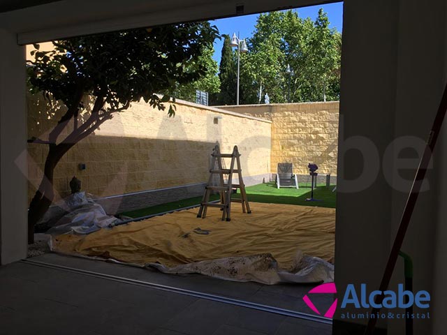 Montaje y Colocación de una Cortina de Cristal abatible en el Patio Interior de una casa ubicada en Dos Hermanas, Sevilla