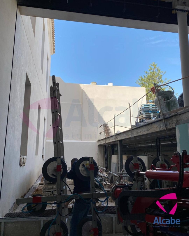 Traslado e instalación de cristales para cerramiento de varias zonas y estancias del Ayuntamiento de Fuentes de Andalucía, en Sevilla.