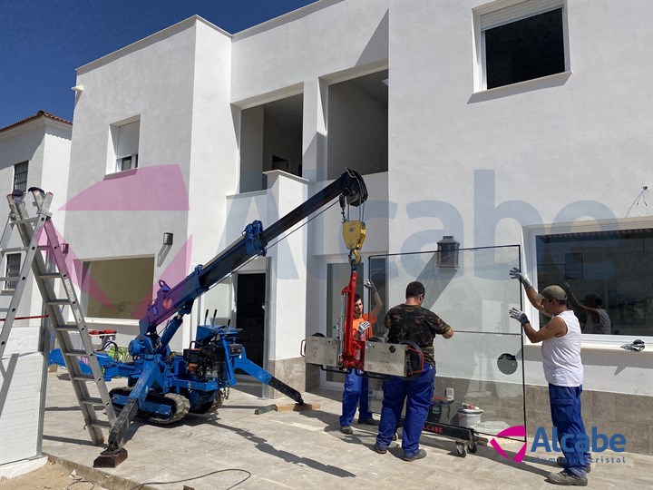 Elevación y colocación de cristales con minigrúa, en vivienda unifamiliar de Huelva